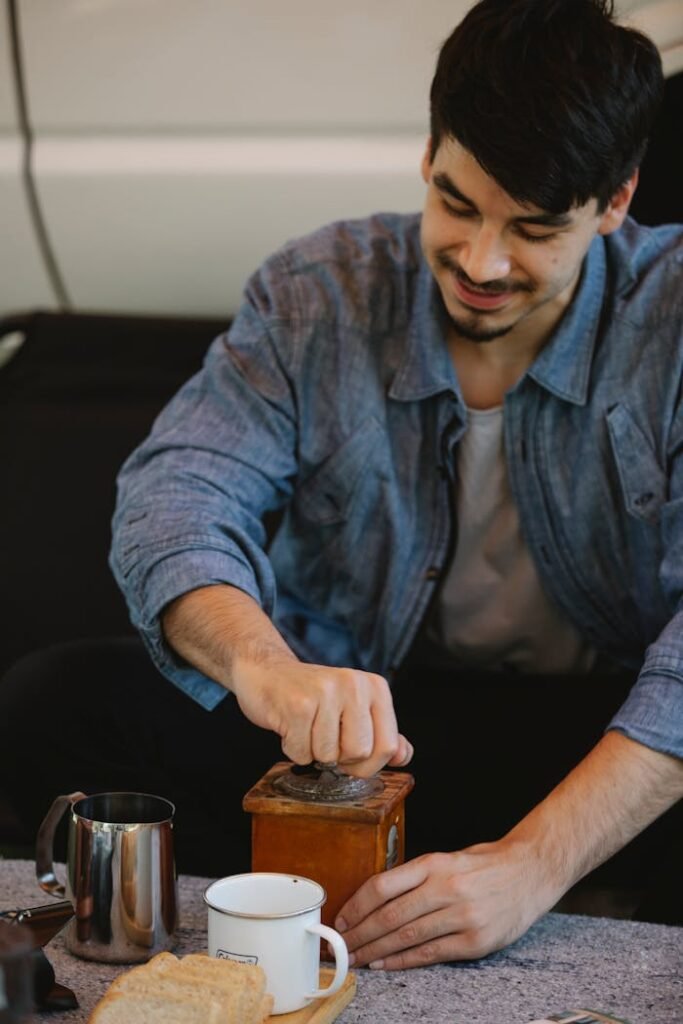 Crop content young man grinding coffee in manual grinder